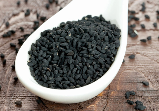 Semi di cumino nero (Nigella sativa) in un contenitore di vetro. I piccoli semi neri a forma di mezzaluna da cui si estrae l'olio benefico.
