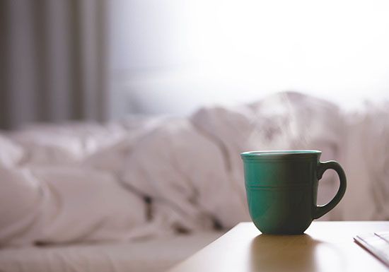Tazza di tisana calda e letto preparato, simbolo di routine serale per un sonno riposante