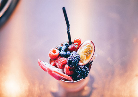 Calice colmo di frutti di bosco freschi (lamponi, mirtilli, more), alimenti ricchi di antiossidanti naturali benefici per contrastare il colesterolo ossidato.
