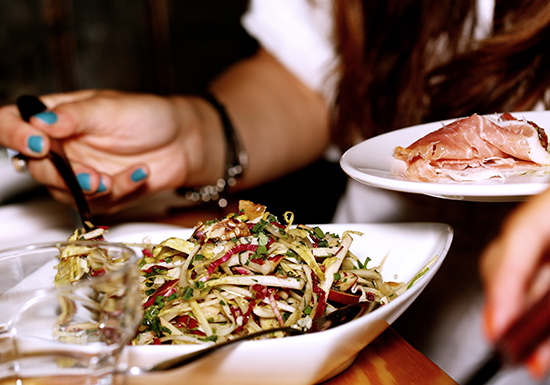 Donna che mangia un pasto sano, rappresentazione del processo digestivo che inizia nello stomaco con l'acido cloridrico.